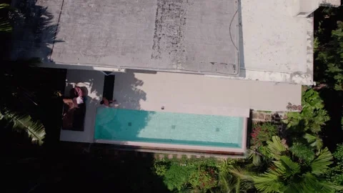 Top view Drone shot of a Man Enjoying a Swim in a Pool by a fancy House,daytime Stock Footage 278355535