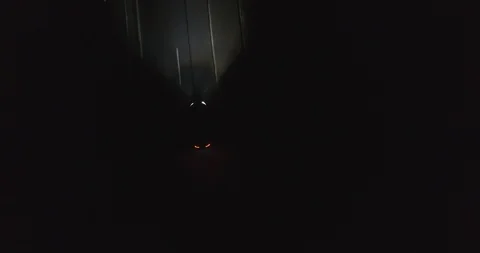 Top view drone shot at night of car with intensive headlights driving on a Video stock 123919437