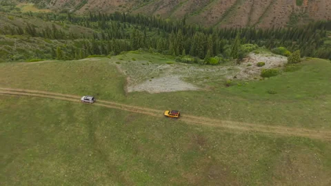 Top view drone shot of two off-road SUVs driving across Video stock 334910468