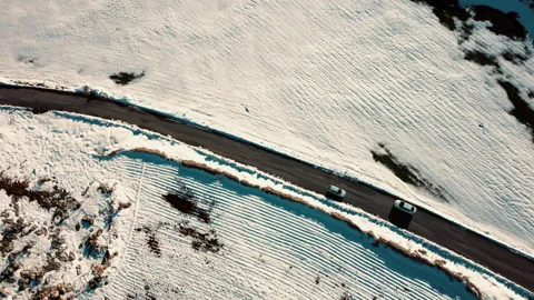 Top view drone video of two vehicles coming on a snowy road. Stock Footage 237641776