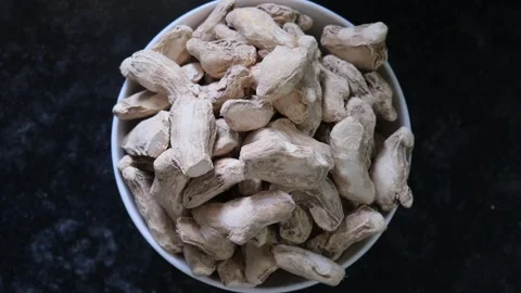 Top view of dry ginger roots in white ceramic bowl on black background Video stock 331987484
