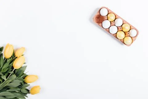Top view of Easter eggs and yellow tulips on a white table 库存照片