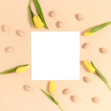 Top view of easter eggs and flowers on a beige background. Stock Photos