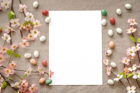 Top view of Easter eggs and flowers on a beige background with greeting card. Stock Photos