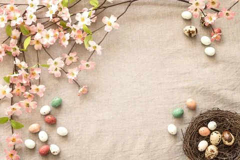 Top view of Easter eggs, nest and flowers on a beige background with copy space. Stock Photos