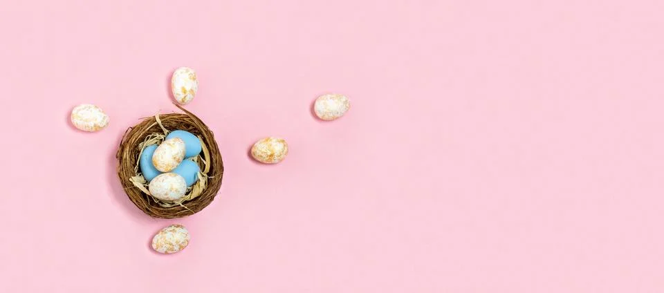 Top view Easter eggs in nest on pink background. Wide banner. Stock Photos