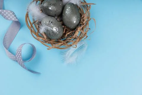 Top view Easter eggs nest with ribbon on blue background Fotos de archivo