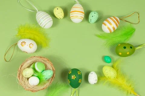 Top view of Easter eggs painted in different patterns and feathers on a green Stock Photos