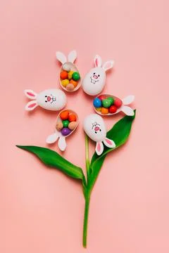 Top view Easter pink background with flower shape made of funny eggs containers Stock Photos