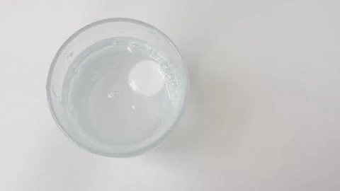 Top view of an effervescent tablet dissolving in a glass of water, releasin.. Stock Footage 335141473