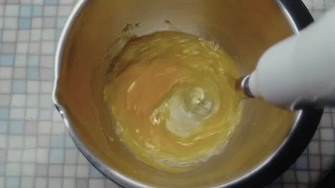 Top view, elderly womans hand with mixer beating chicken eggs in metal bowl on Stock Footage 318853383