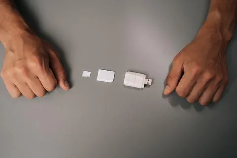 Top view of electronic technician comparing memory card sizes, from smallest to Foto stock