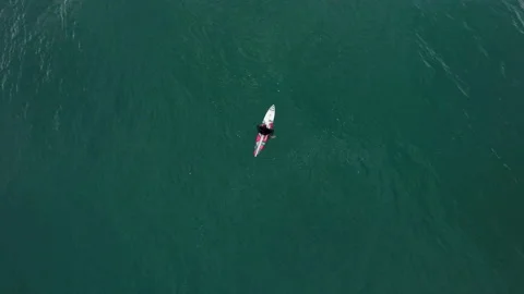 Top view of elite surfer sitting on surfboard and floating on ocean surface Stock Footage 156041669