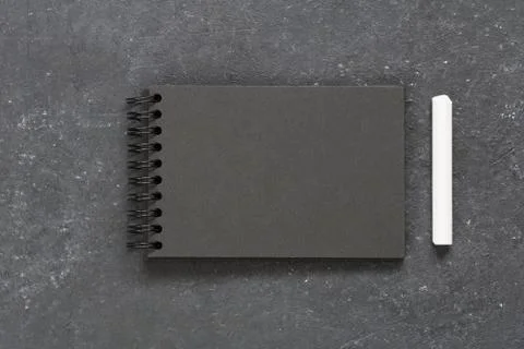 Top view on the empty black notepad with white chakl on the black table. Copy Stock Photos