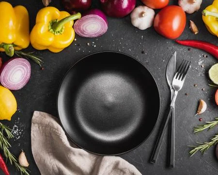 Top view of the empty black plate among fresh vegetables, herbs and spices on Stock Photos