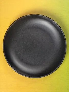 Top view of an empty black plate on a bright yellow gradient background Stock Photos