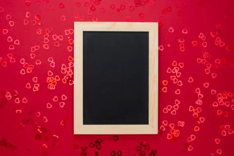 Top view of empty blackboard on red background with shiny confett. Stock Photos