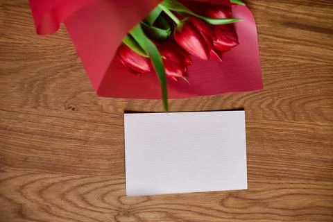 Top view empty card with  red tulips flowers in red paper wrapper with gift b Stock Photos