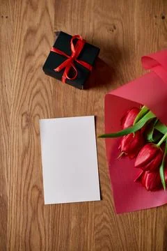 Top view empty card with  red tulips flowers in red paper wrapper with gift b Stock Photos