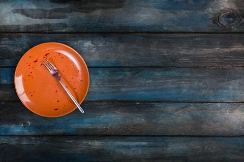 Top View. Empty ceramic plate with a fork on a colored wooden background. Red Stock-Fotos