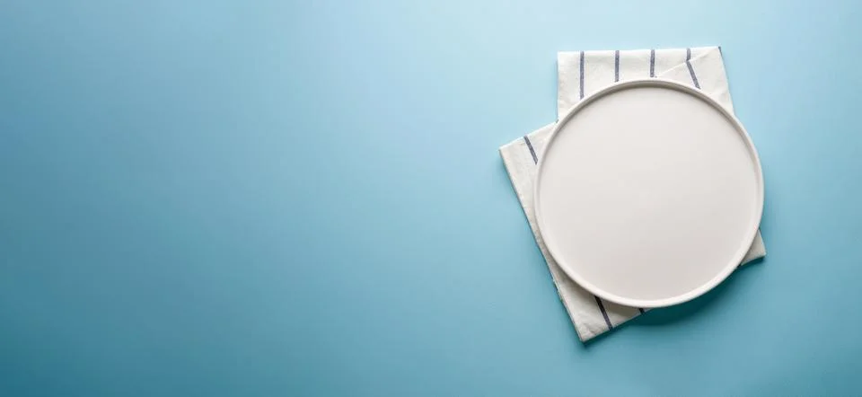 Top view of empty ceramic white plate on blue background Stock Photos