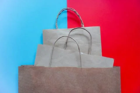 Top view of empty craft paper bags on blue and red background. Flat lay on co Stock Photos