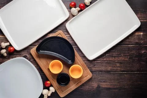 Top view of empty dinner plates with vegetables around them on wooden table Stock Photos