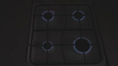 Top view of empty gas stove with four blue glowing flames in holes against dark Stock Footage 268765091