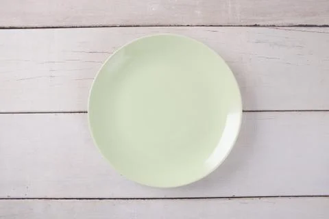Top view of empty green plate put on white wood table with space for copy. Stock-Fotos