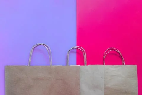 Top view of empty line of craft paper bags on purple and pink background. Fla Stock-Fotos