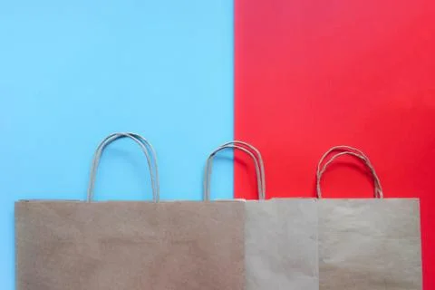 Top view of empty line of craft paper bags on blue and red background. Flat l Stock Photos