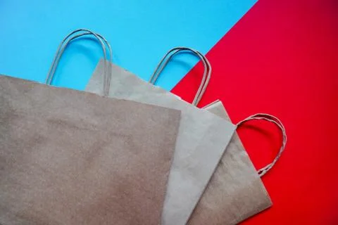 Top view of empty line of craft paper bags on blue and red background. Flat l Stock Photos