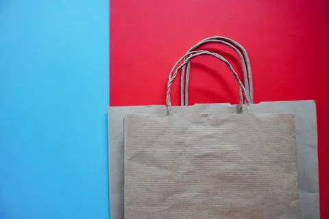 Top view of empty line of craft paper bags on blue and red background. Flat l Stock Photos