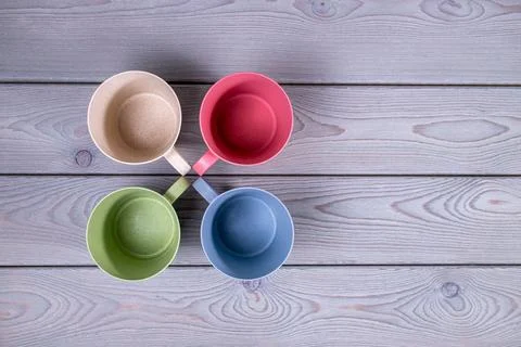 Top view of the empty multicolored mugs on a wooden table. Copy space Stock Photos