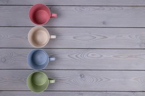 Top view of the empty multicolored mugs on a wooden table. Copy space Stock Photos