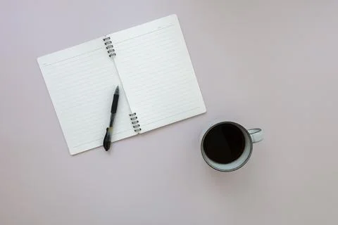 Top view of empty notebook with pen above cup of black coffee on pink background Stock Photos
