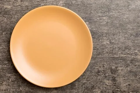 Top view of empty orange plate on cement background. Empty space for your d.. Stock Photos