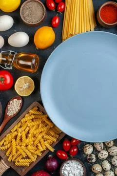 Top view empty plate around eggs tomatoes seasonings and italian pasta on d.. Stock Photos