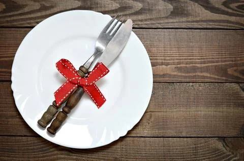 Top view of empty plate with knife and fork decorated with red ribbon. Foto stock