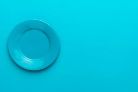 Top view of empty round blue plate on turquoise blue background with copy space Stock Photos