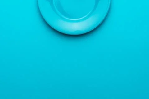Top view of empty round blue plate on turquoise blue background with copy space Stock Photos