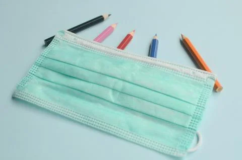 Top view empty space with colored pencils and masks on a blue background Stock Photos