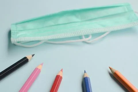 Top view empty space with colored pencils and masks on a blue background Stock Photos