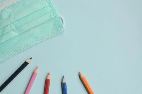 Top view empty space with colored pencils and masks on a blue background Stock Photos
