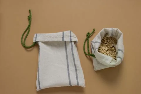 Top view empty textile bag and oatmeal in textile bag flat lay on a beige bac Stock Photos