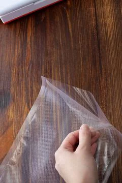 Top view of an empty vacuum bag in a woman's hand on a dark Stock Photos