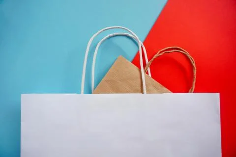 Top view of empty white and craft paper bags on blue and red background. Flat Stock Photos