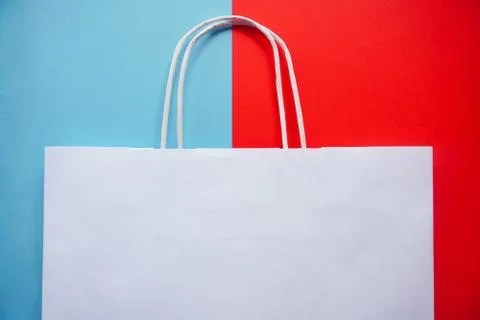 Top view of empty white paper bag on blue and red background. Flat lay on con Stock Photos