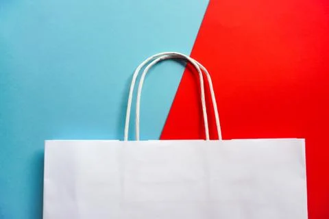 Top view of empty white paper bag on blue and red background. Flat lay on con Foto stock