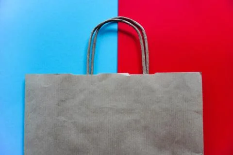 Top view of empty white paper bag on blue and red background. Flat lay on con Stock Photos